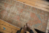 Distressed vintage Oushak runner with faded burnt orange and dusty gold rococo motifs.