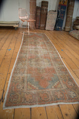 Corner detail of distressed Oushak runner with checkered spandrel and faded orange, slate blue.