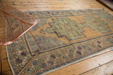 Distressed vintage Turkish Oushak rug corner, sage green germinating plant motifs.