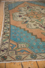 Distressed Oushak rug corner, showing pale aqua field with stepped spandrel and border.
