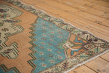 Oushak rug corner showing pale aqua field, dusty gold stepped spandrel, and textured wear.