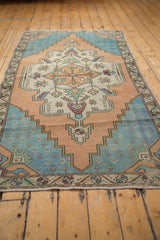 Distressed Oushak runner end border with pale aqua, ivory, stylized floral motifs, and fringe.