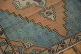 Distressed Oushak rug spandrel showing stepped aqua, dusty gold, green, and aubergine patterns.