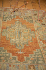 Distressed Oushak rug's central medallion pattern with soft terra cotta and celadon green.