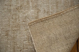 Underside of a distressed vintage Oushak carpet showing hand-knotted foundation and secured edge.