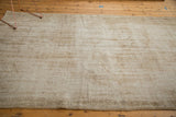 Distressed Oushak rug corner showing textured pile and varied ivory, beige, faded blue hues.