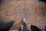 Distressed Oushak rug with blush, slate blue, and gold ram's horn medallion.