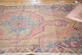 Distressed vintage Turkish Oushak rug with faded blush, blue, and vibrant pink floral detail.