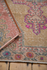 Distressed Oushak rug border with blush, slate blue, and violet floral motifs.