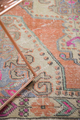 Distressed Oushak rug, showing visible texture and simplified floral patterns in muted tones.