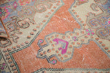 Distressed Oushak rug pile revealing faded tangerine, ivory, and fuchsia tones.