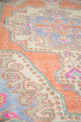 Time-softened pile of distressed Oushak rug in tangerine, ivory, and slate blue rococo motifs.