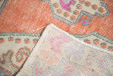 Faded tangerine distressed Oushak pile, intact selvage, and knotted reverse with fuchsia tones.