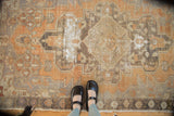 Distressed Oushak rug showing geometric patterns, worn texture, and exposed foundation.