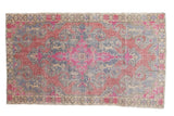 Distressed Oushak rug features a dramatic medallion in vivid pink, blue, beige tones.
