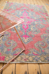 Distressed Oushak rug detail: fuchsia and slate blue scalloped contours with visible wear.