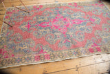Distressed Oushak rug detail: fuchsia and slate blue pattern with beige tones, original selvage.