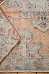 Distressed Oushak rug close-up, revealing even wear to knot heads, faded orange, fuchsia, and beige.