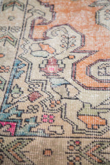 Textural close-up of distressed Oushak rug's curvilinear motifs, showing faded orange, pink, and blue.