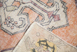 Distressed vintage Oushak rug corner, showing faded orange pattern, even pile wear, and reverse.