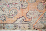 Distressed vintage Oushak rug with faded burnt orange and ivory scrolling contours.