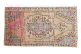Vintage distressed Oushak rug with a rococo medallion, featuring bright pink and blue accents on an ivory field.