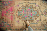 Stylized medallion of a distressed Oushak rug showing pops of bright pink and slate blue.