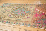 Stylized rococo medallion with bright pink and sky blue details on a distressed Oushak rug.