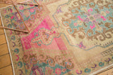 Evenly worn texture of a distressed Oushak rug with vibrant bubble gum pink and sky blue rococo details.
