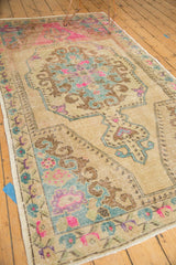 Perspective view of a distressed Oushak rug's ivory field and colorful rococo medallion.