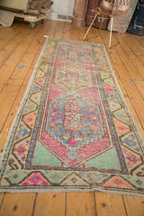 Vintage distressed Oushak runner corner, revealing soft mint green, pink, and worn geometric patterns.