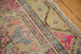 Playful pink, blue, and gold patterns with visible wear on a vintage Oushak rug.