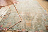 Distressed Oushak rug with faded European floral motifs, visible foundation, and soft colors.