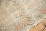 Textured close-up of distressed Oushak rug, revealing worn foundation and knot heads in soft hues.