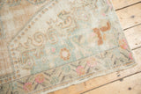 Hard-worn Oushak rug corner with visible foundation and subtle peach-green pattern.