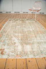 Distressed Oushak rug edge showing original selvage, worn foundation, faded peach and beige patterns.
