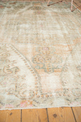 Textural view of a distressed vintage Oushak rug with worn pile, faded peach, and beige tones.