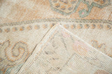 Distressed vintage Oushak rug showing exposed foundation, light knot heads, and original selvage.