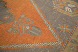 Geometric stepped contour design on burnt orange and charcoal fields of a vintage Oushak rug.