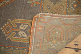 Vintage Oushak rug corner revealing tightly woven foundation, orange edge, and charcoal patterned pile.