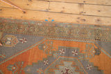 Stepped geometric spandrel and border patterns on a burnt orange and charcoal Oushak rug runner.