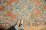 Decorative vintage Distressed Oushak rug section with bold scrolling motifs and striking terra cotta, pink, blue.