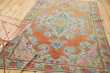 Distressed vintage Oushak rug corner featuring pale terra cotta, ivory spandrel, and pink florals.