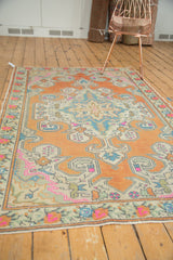 Distressed Oushak rug close-up showcasing pale terra cotta and vivid pink motifs.