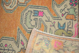 Distressed Oushak rug pile with pale terracotta and green geometric motifs, showing reverse.