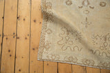 Distressed vintage Oushak rug runner's soft ivory pile and pale coffee cloudband motifs.