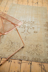 Distressed ivory Oushak rug corner showing faded cloudband design and worn texture.