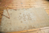 Lower section of distressed vintage Oushak runner with faded ivory and pale coffee brown patterns.