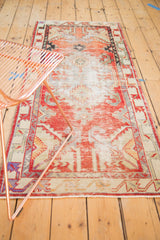 Distressed Oushak runner's faded cherry red starburst spandrels and serpent-inspired border.