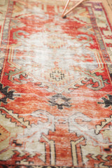 Distressed texture of a hand-knotted Oushak runner with faded cherry red and ivory patterns.